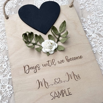 A wooden sign with a heart with space for writing a date. The sign says "Days until we become Mr and Mrs Sample"