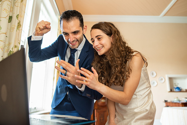 Couple clapping in front of laptop screen