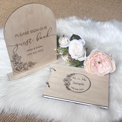 A wooden guestbook for guests to sign and a sign which says "Please sign our guestbook". Both the sign and the guestbook have "Mr and Mrs" on.