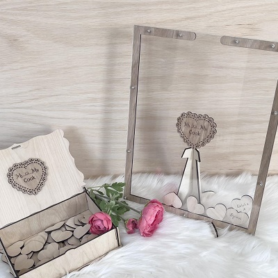 A box with wooden hearts people can write on. There is a wooden frame with glass where people can drop the hearts after writing.