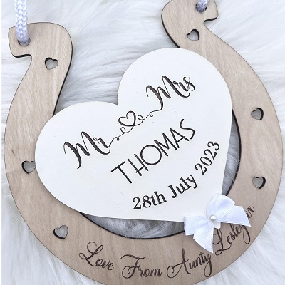 A wooden horseshoe and a white plaque which has "Mr and Mrs Thomas and a date on it.