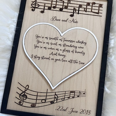 A wooden keepsake carved with a heart and song lyrics.